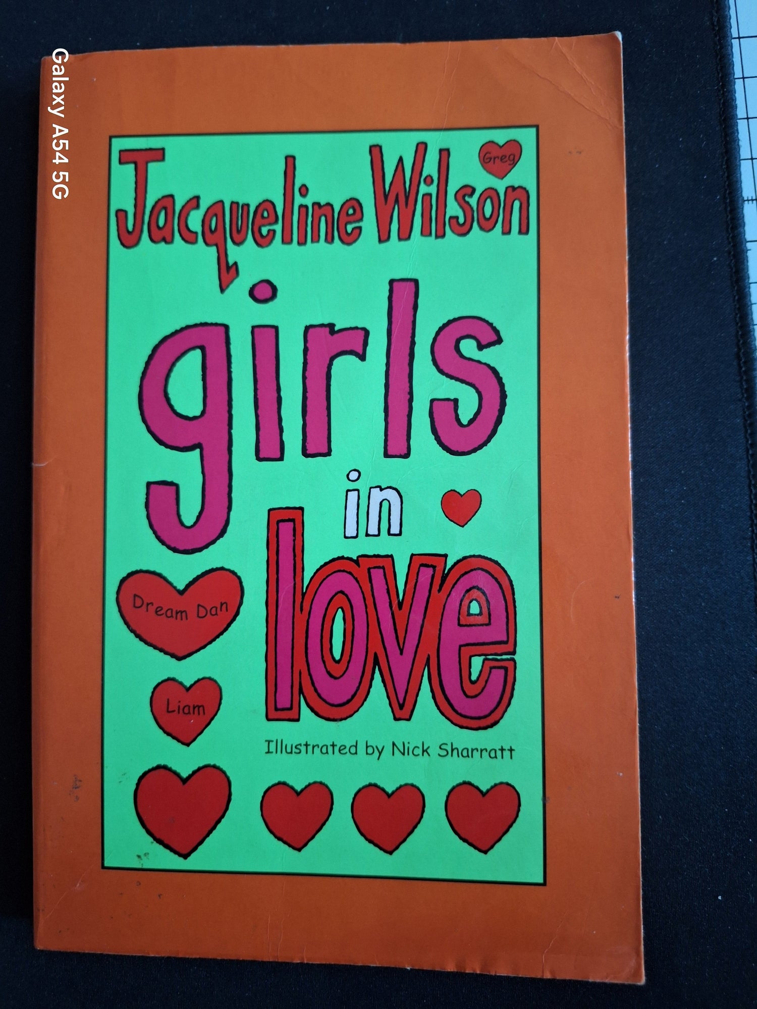 Book cover of Girls in Love by Jacqueline Wilson with illustrated red hearts on green and orange background