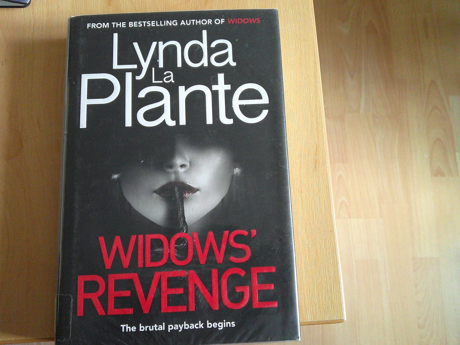 Lynda La Plante Widows Revenge book cover featuring a mysterious woman with a dark background