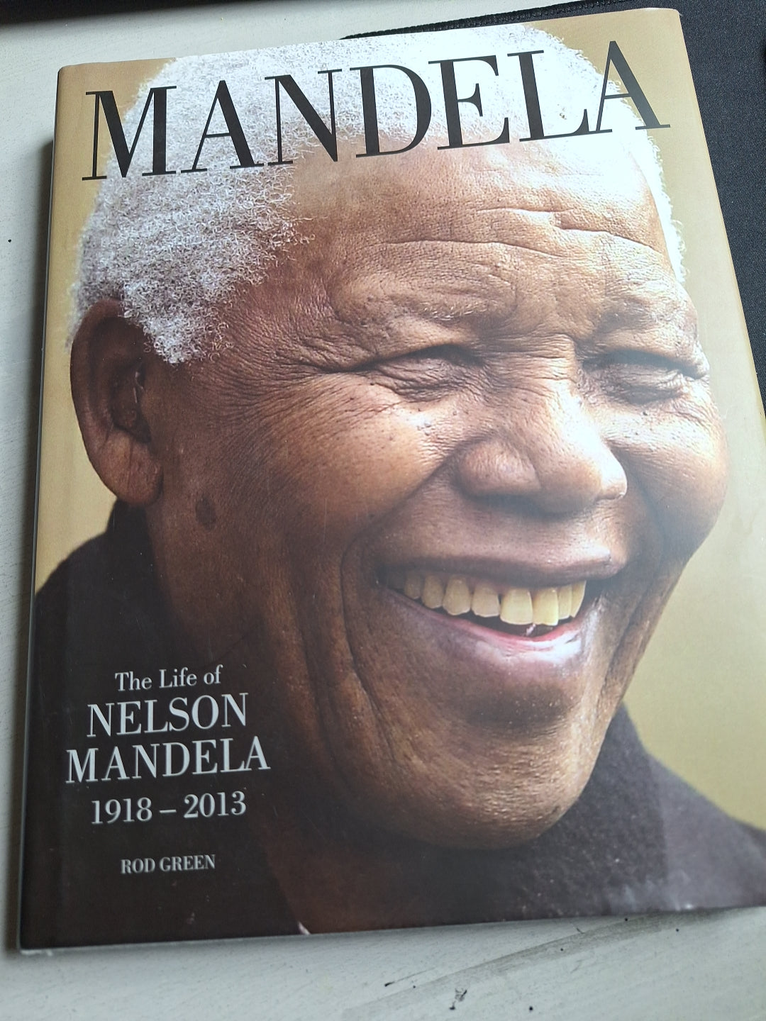 Slightly read book titled Mandela featuring a close-up portrait of Nelson Mandela smiling