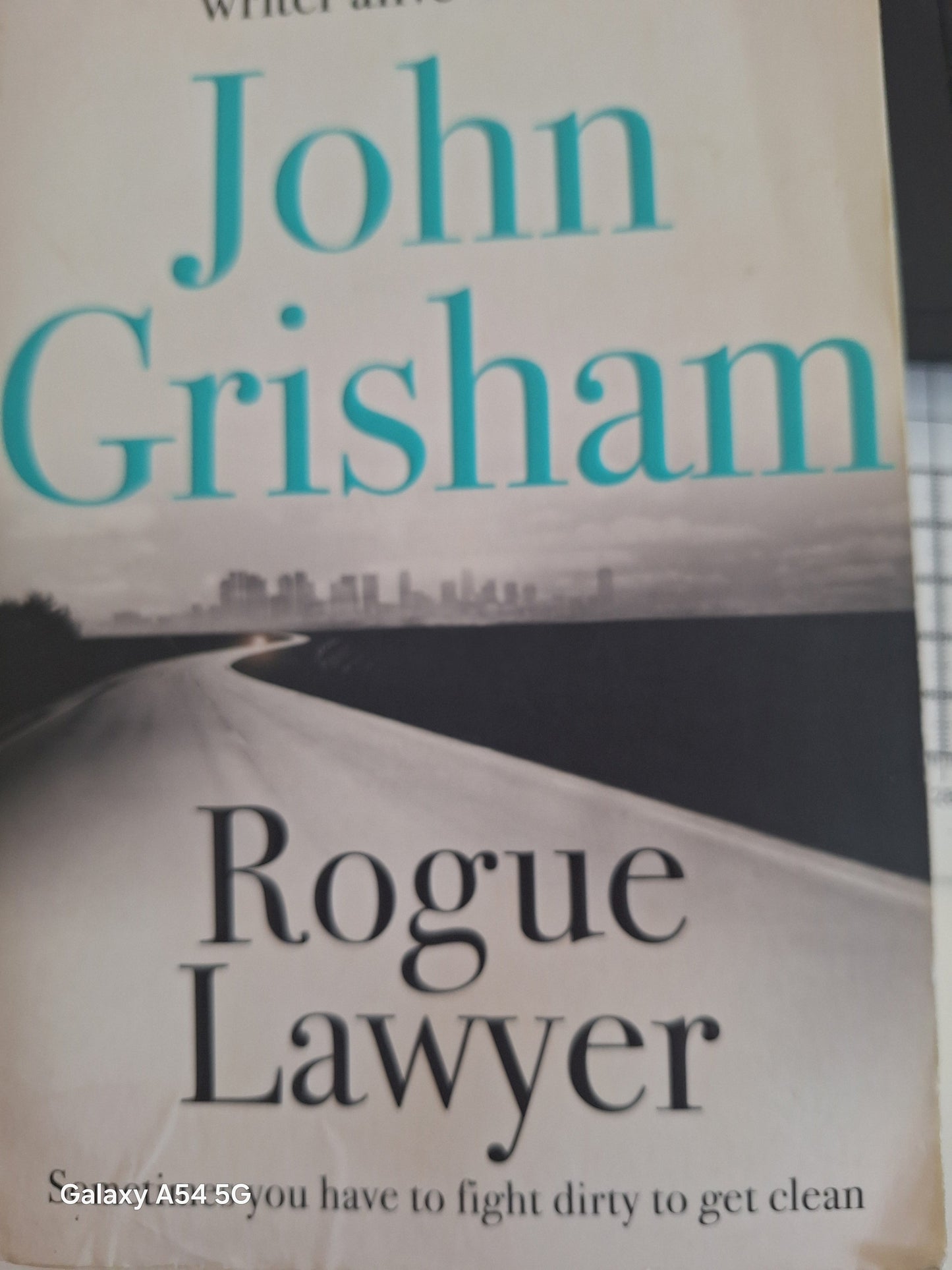Second hand John Grisham novel Rogue Lawyer featuring a road image on the cover